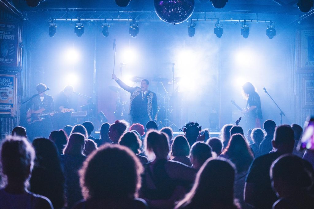 Live entertainment in a venue, stage washed in blue with the crowd in silhouette