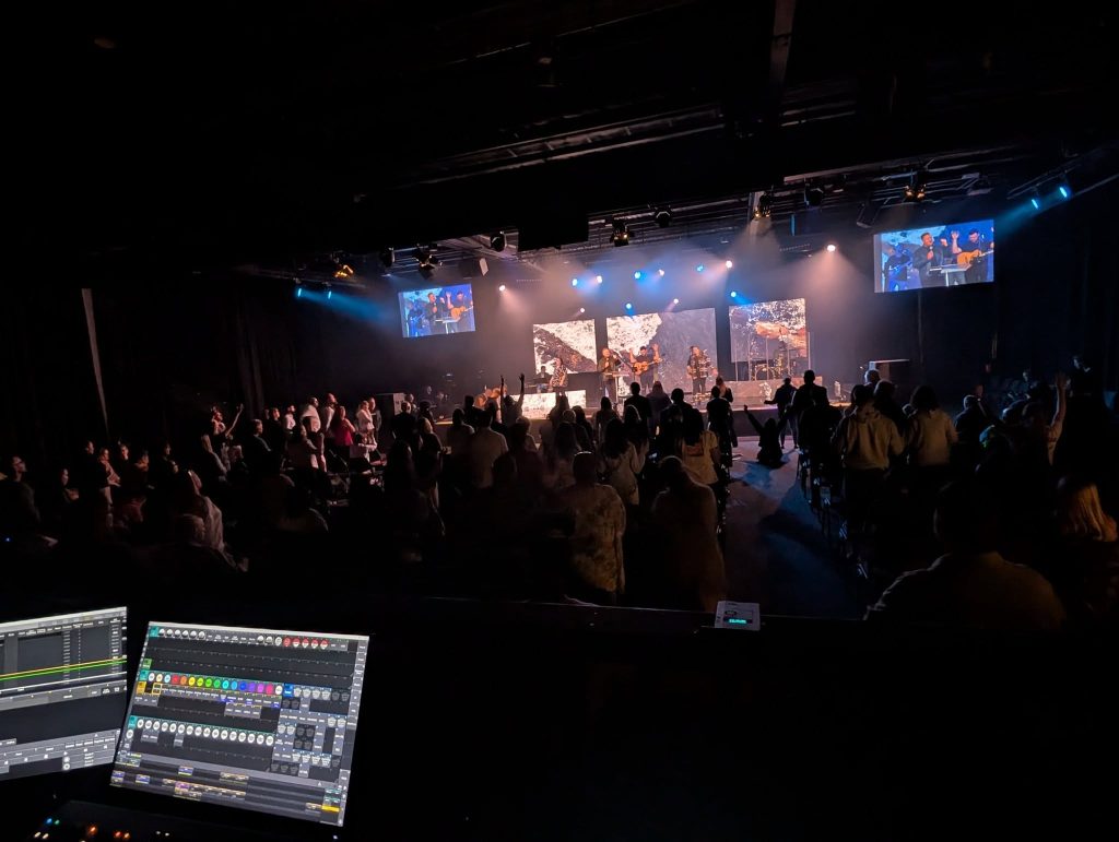 View from the front-of-house console over a packed venue during a live event