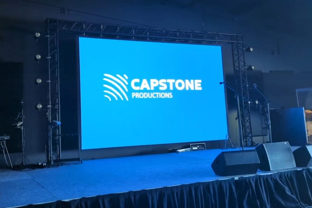 A Capstone Productions LED video wall on truss, flanked by stage lighting